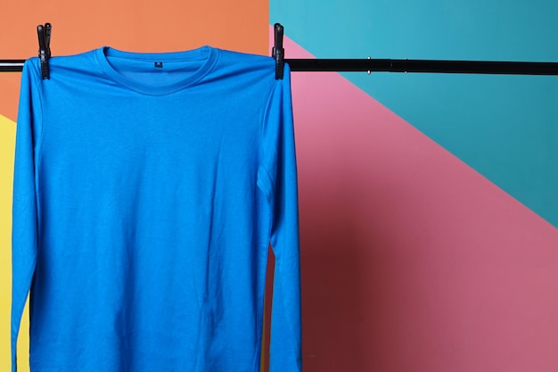 Maqueta de camiseta azul colgando sobre fondo colorido