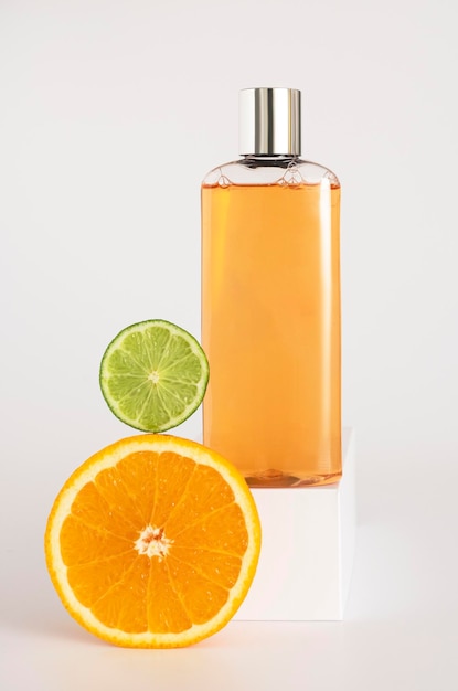 Maqueta de champú o gel de ducha en un podio cuadrado, naranja y lima se encuentran cerca