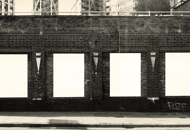 Maqueta de una colección de carteles en una pared de ladrillos de una ciudad en blanco y negro