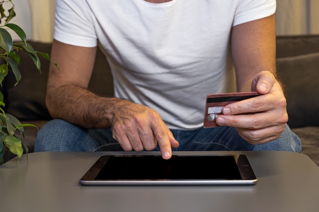 Foto maqueta de compras en línea. hombre pagando el pedido en línea con la tableta y la tarjeta de crédito desde casa