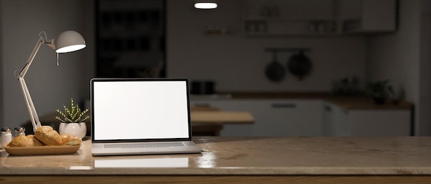 Maqueta de computadora portátil y espacio de copia en la mesa sobre una cocina oscura y borrosa en el fondo