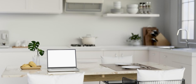 Una maqueta de computadora portátil en una mesa de comedor en una cocina blanca moderna