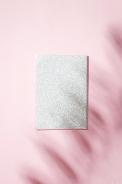 Maqueta de cuaderno blanco en blanco con sombra de hojas sobre fondo rosa