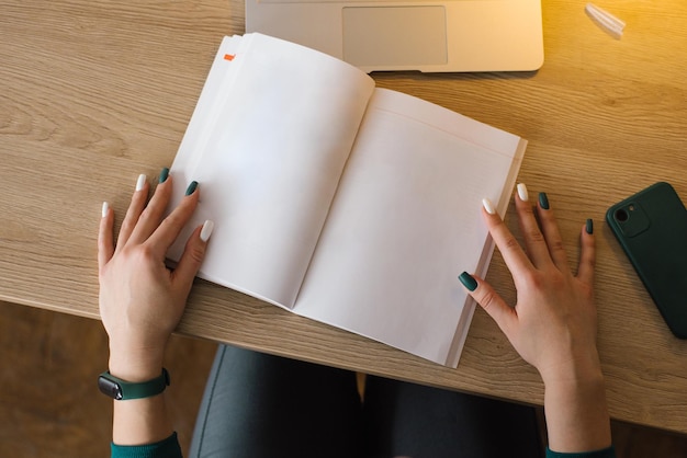 Maqueta de un cuaderno o libro abierto en manos de una mujer joven en un escritorio