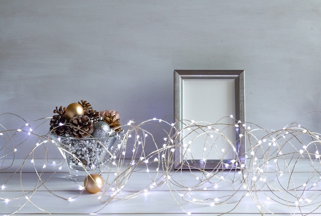 Maqueta de decoración navideña en un marco con conos, luces navideñas en un espacio de copia de mesa blanca