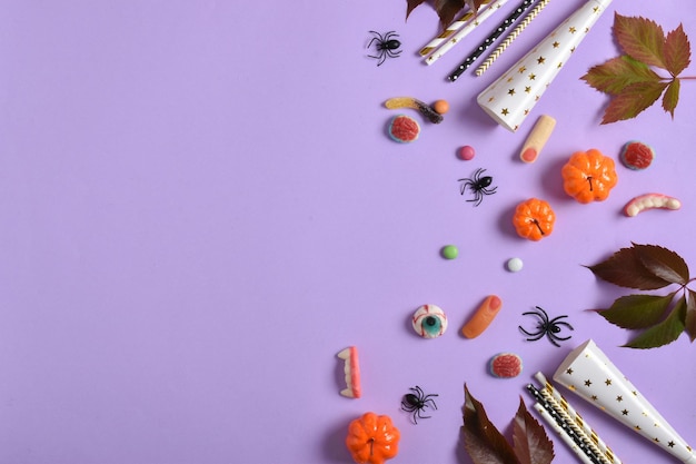 Una maqueta con decoraciones de Halloween con calabazas y dulces sobre un fondo morado con un lugar para texto Un lugar para copiar Vista superior de posición plana