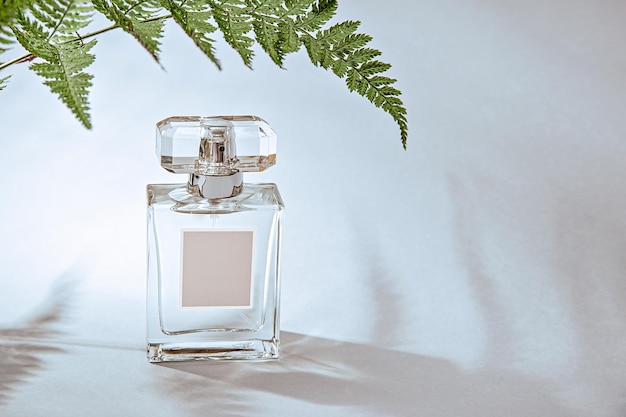 Una maqueta para el diseño de la etiqueta con una botella de perfume adornada con una hoja de helecho y una luz caprichosa