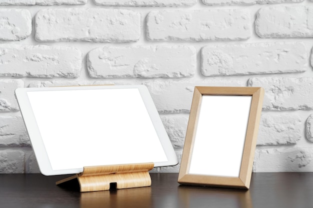 Maqueta de espacio de trabajo creativo con tableta de pantalla en blanco y marco de fotos