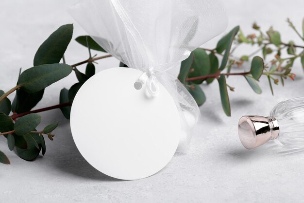 Maqueta de etiqueta de regalo blanca redonda con hojas de eucalipto sobre fondo gris maqueta de etiqueta de etiqueta Etiqueta de favor de boda