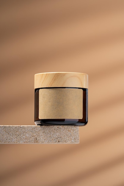 Maqueta de frasco de vidrio de ámbar con crema facial en estante de piedra natural Bálsamo cremoso facial con aceites esenciales o péptidos para el cuidado antienvejecimiento de la piel de la mujer en maqueta de fondo beige