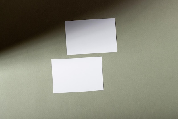 Maqueta con hojas de papel horizontales en blanco con espacio de copia Luz solar dura y sombras sobre un fondo verde Plantilla para diseño comercial Vista superior plana