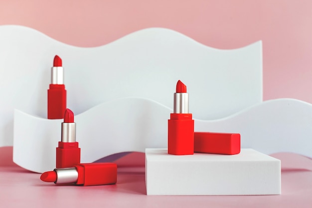 Maqueta de lápices labiales rojos en una escalera blanca con formas geométricas y un podio