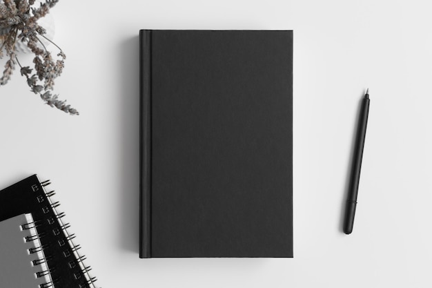 Foto maqueta de libro negro con lavanda y accesorios de espacio de trabajo en una mesa blanca