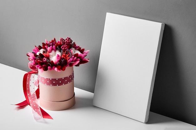 Maqueta de lienzo en blanco con flores secas sobre fondo de pared gris