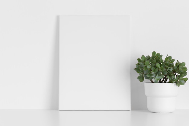 Maqueta de lienzo blanco con una planta suculenta sobre la mesa