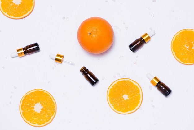 Maqueta de marca. Aceite esencial natural, envases de botellas de cosméticos con rodajas de naranja.