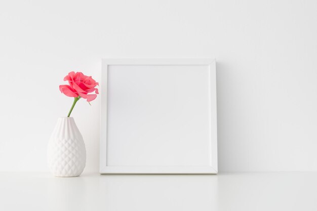 Maqueta de marco cuadrado blanco con rosa rosa en un jarrón