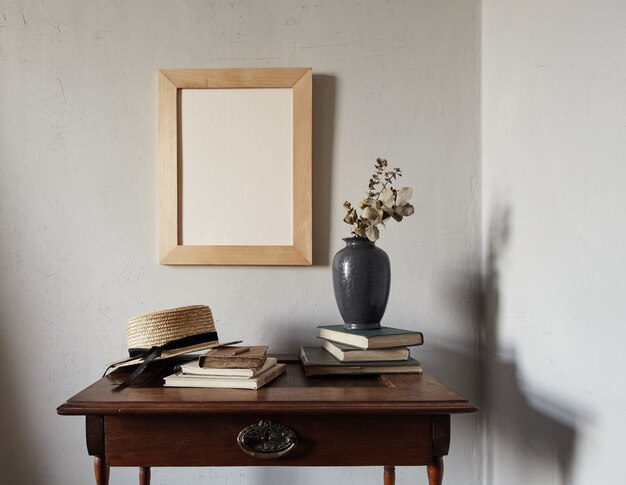 Maqueta de marco de madera. composición con cuaderno, libros, jarrón con flores secas sobre una vieja mesa de madera. Interior francés moderno.