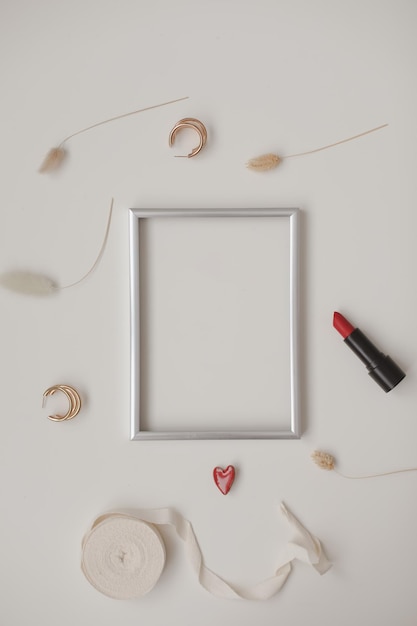 Maqueta de moda mínima con marco de fotos vacío y lápiz labial rojo y accesorios para mujer en blanco