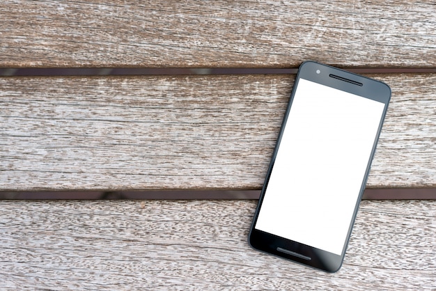 Maqueta móvil del teléfono inteligente con pantalla en blanco sobre fondo de madera.