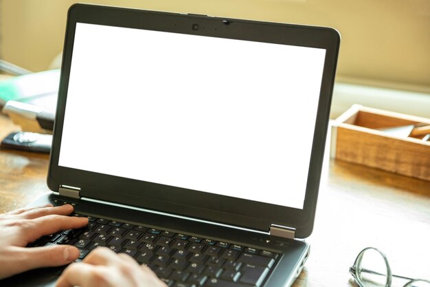 Maqueta de pantalla de computadora portátil con pantalla blanca en blanco en un espacio de copia de fondo de oficina de escritorio de madera