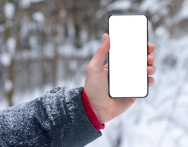 Maqueta de pantalla de teléfono inteligente de teléfono móvil en mano en clima frío de invierno con nieve
