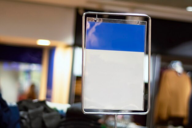 Maqueta de papel azul-blanco de un letrero de descuento en el fondo de una tienda con ropa.