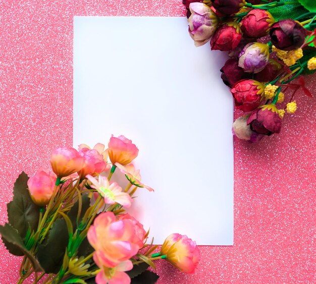 Maqueta de papel blanco en blanco y ramo de flores sobre fondo rosa Tarjeta de felicitación del Día de San Valentín o del Día de la Madre