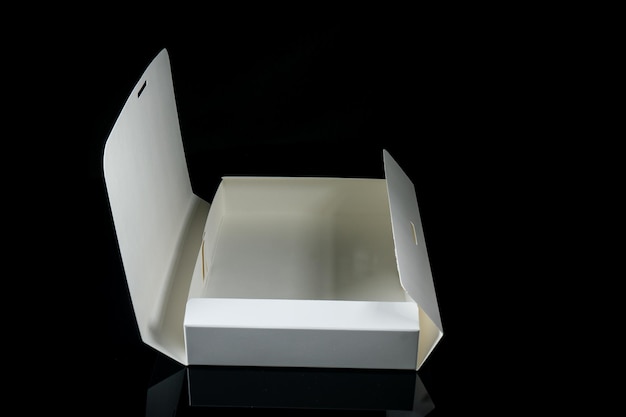 Maqueta de paquete en blanco Caja de papel blanco sobre fondo de yeso negro Vista superior