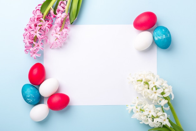 Maqueta de primavera con huevos de Pascua, jacintos y blanco de papel blanco sobre fondo azul. Concepto de pascua. Copia espacio Vista superior