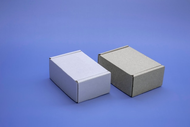 Foto maqueta de primer plano de cajas de cartón con espacio de copia. dos cajas de corton: marrón y blanco sobre fondo azul. concepto de embalaje, regalos, entrega.