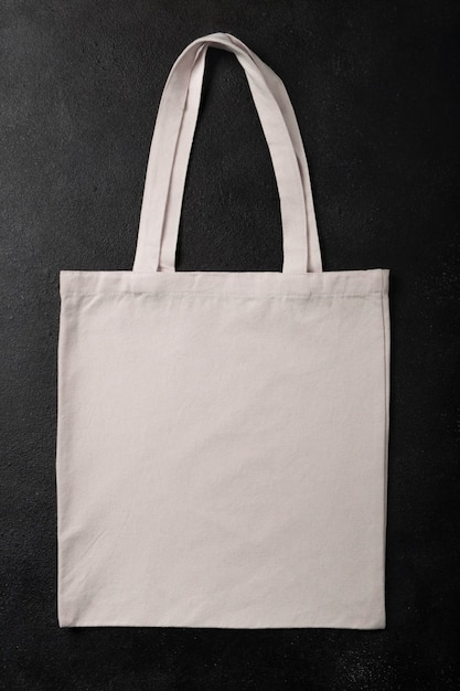 Maqueta de saco de compras ecológico de tela de lona de bolso de comprador blanco para su diseño, plantilla aislada sobre fondo negro con textura con espacio de copia. Endecha plana.