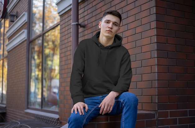 Maqueta de una sudadera con capucha vacía en un chico joven en jeans, vista frontal. Plantilla de capota negra para publicidad en la tienda online. Ropa casual para presentación de diseño.