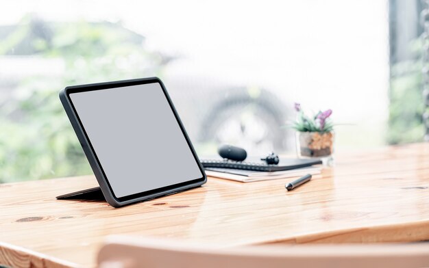 Maqueta de tableta de pantalla en blanco y lápiz óptico sobre mesa de madera.