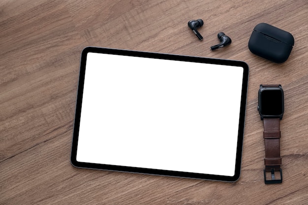 Maqueta de tableta de pantalla en blanco, reloj inteligente y auriculares en la mesa de madera