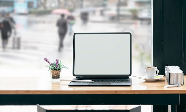 Maqueta de tableta de pantalla en blanco con teclado en mesa de madera en café.