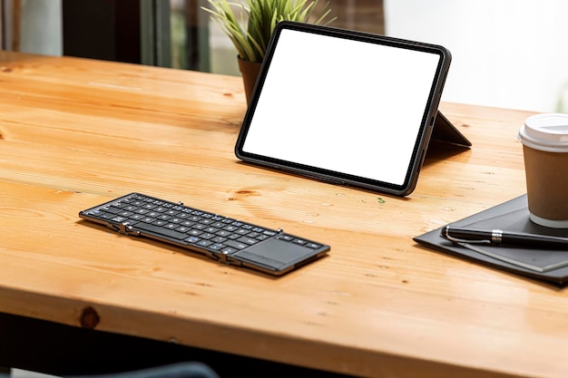 Maqueta tableta portátil de pantalla en blanco suave y teclado en la mesa de madera. Concepto de espacio de trabajo creativo.