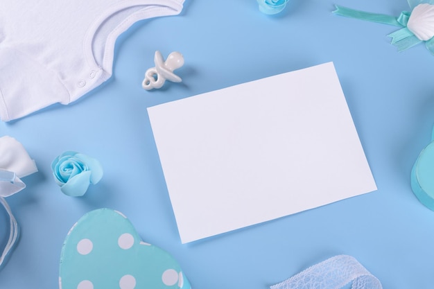 Maqueta de tarjeta de invitación de baby shower 5x7 con accesorios de bebé, pezón de mono o caja de regalo ficticia de bebé con espacio de copia sobre fondo de color azul pastel