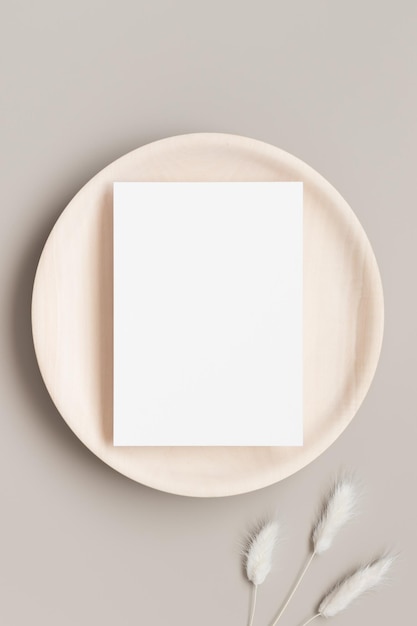 Maqueta de tarjeta de invitación blanca en una placa de madera con una relación de 5x7 de decoración de lagurus similar a A6 A5