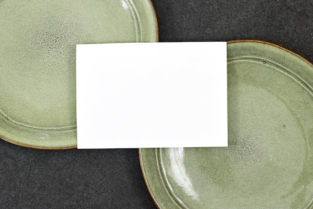 Foto maqueta de tarjeta de invitación de boda por encima de una placa de cerámica verde sobre un fondo gris maqueta de carta en blanco