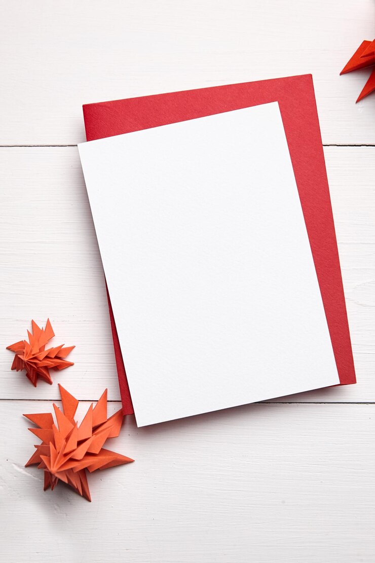Maqueta de tarjeta de navidad con sobre y abetos de papel rojo sobre fondo blanco de madera vista superior plana