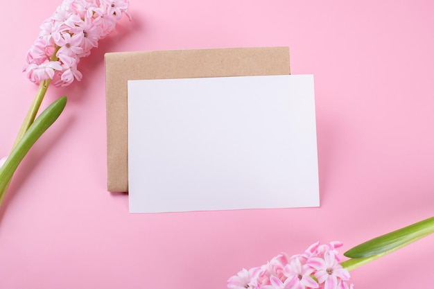 Maqueta de tarjeta de papelería de invitación de boda en blanco con sobre sobre fondo rosa con flores de jacinto, blog femenino. Tarjeta del día de San Valentín, fondo del día de San Valentín, día de la madre