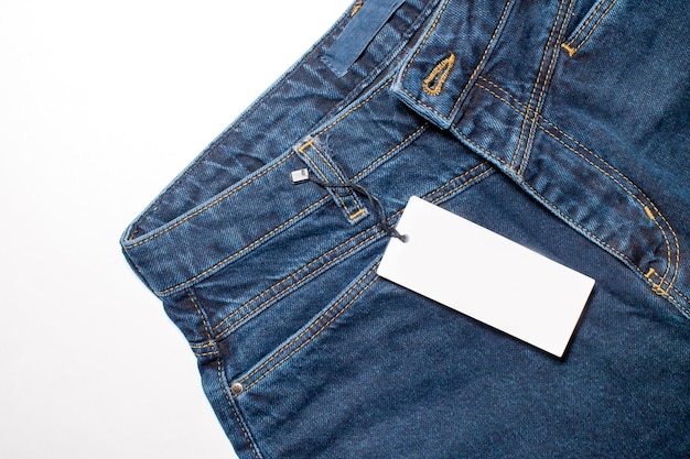 Maqueta de una tarjeta de precio blanca para ropa en pantalones de mezclilla azul
