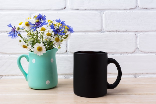 Maqueta de taza de café negro con aciano y margarita en jarra