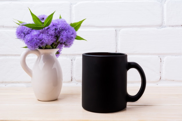 Foto maqueta de taza de café negro con ageratum azul en jarra