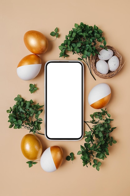 Maqueta de teléfono inteligente con dulces de huevos de oro de Pascua y flores sobre fondo rosa pastel Concepto de vacaciones Felices Pascuas