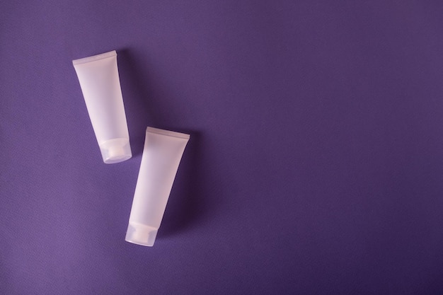 Maqueta de tubo cosmético de plástico en blanco como paquete para crema o loción sobre fondo púrpura