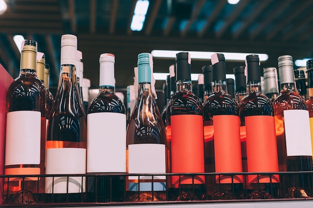 Maquetas de botellas de vidrio con vino rosado en el mostrador de un supermercado.