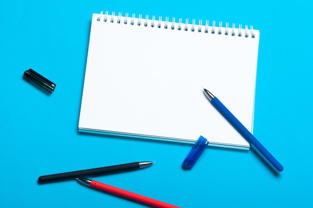 Foto maquete da área de trabalho com vista superior em fundo azul com caderno e caneta