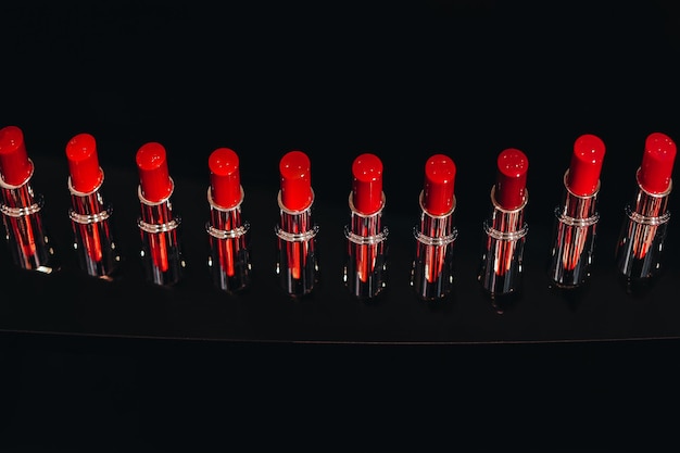 Maquete de batons vermelhos brilhantes em um suporte preto Fundo para apresentação de marca e embalagem Conceito de produto de maquiagem e beleza